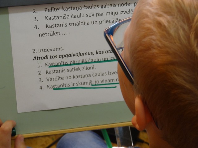 Zēns lasa uzdevumus no lapas.