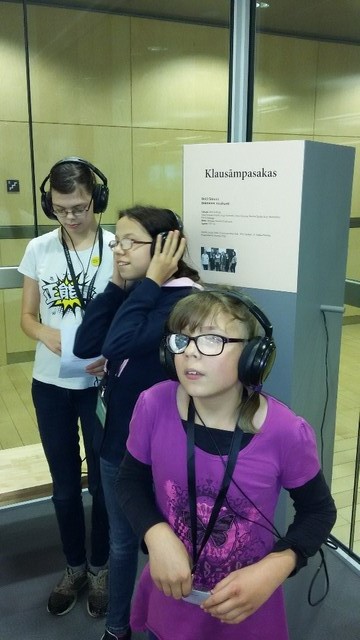 Bērni klausās audioierakstus ar austiņām