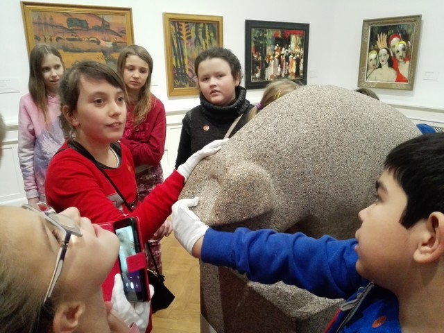 Bērni aptausta muzeja eksponātu - akmens cūku.