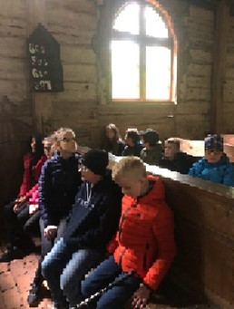 Skolēni sēž koka baznīcā