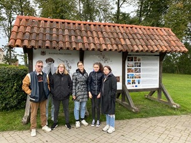 Seši skolēni pie muzeja stenda.