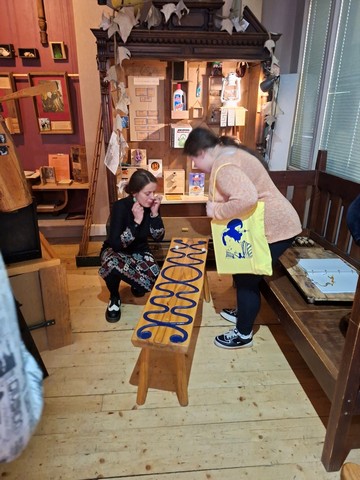 Skolniece apskata eksponātus un sarunājas ar darbinieci.