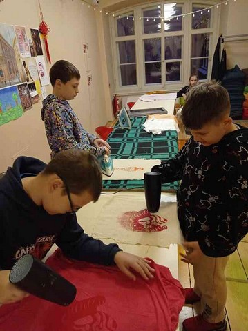 Trīs zēni darbojas ar audumu.