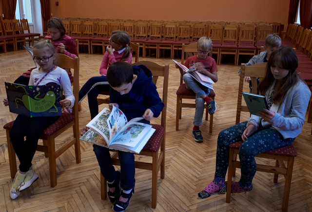 Skolēni lasa un skatās  grāmatas.