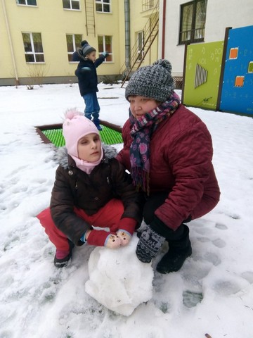 Gabriela ar skolotāju Santu Kurinu sēž pie sniegavīra bubmas.
