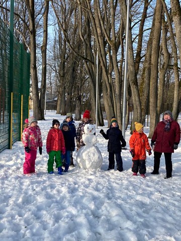 Visi 7 skolēni un skolotāja Santa pie uzceltā sniegavīra.