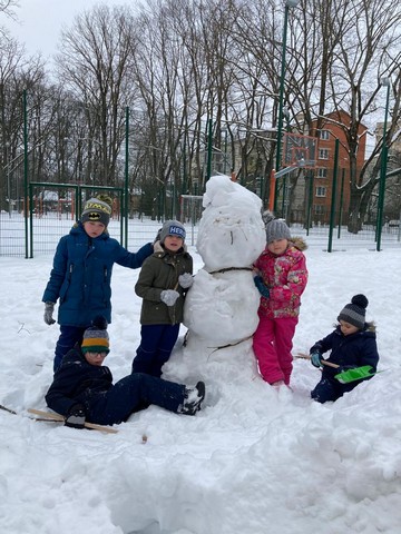 Pieci bērni pie liela sniegavīra.