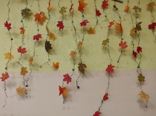Sienas dekorējums, kļavu lapas rudenīgās nokrāsās.