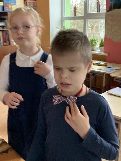 Zēns un meitene klasē dzied himnu