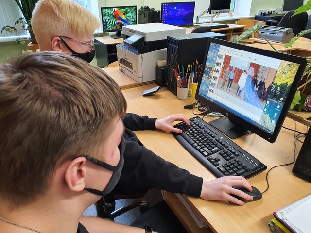 Divi zēni pie datora rediģē fotogrāfijas no skolas uzveduma "Daugava Daugaviņa"