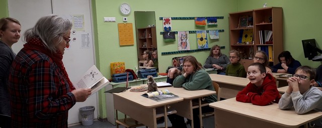 Bibliotēkas darbinieces lasa klases priekšā, skolēni solos klausās.