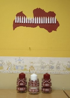 Trīs sveces uz galda ar Latvijas ornamentu rakstiem.