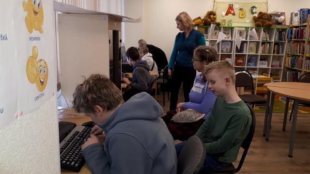 Skolēni sēž pie datoriem un meklē internetā attēlus. 