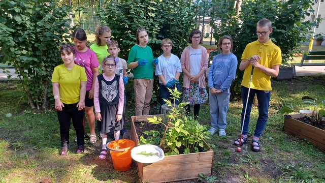 Visi projekta dalībnieki sastājušies pie dobes ar augiem.