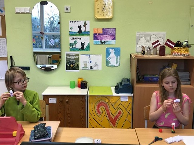 Divi skoleni veido papīra figūriņas.