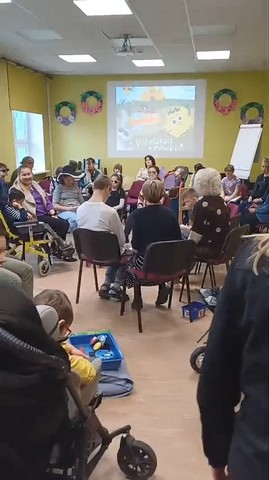 Konferenču zālē visi sēž un sarunājas.