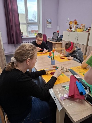 Skolēni pie liela galda gatavo Lieldienu rotājumus.