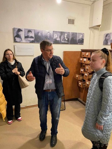 GIds stāsta  telpā ar kartotēku.