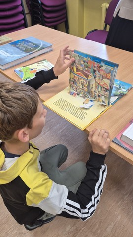 Zēns skatās grāmatu ar lielām krāsainām bildēm.