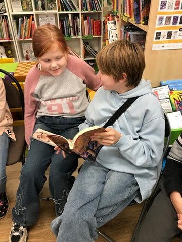 Zēns un meitene skatās grāmatu.