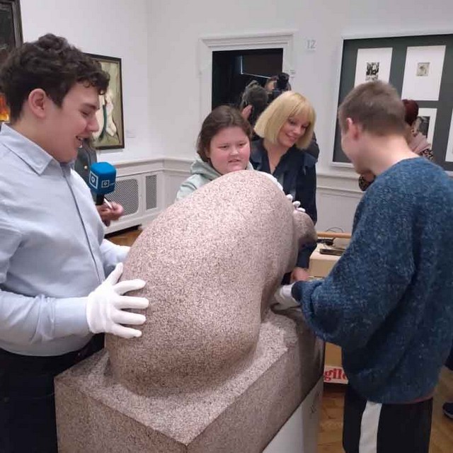 Skolēni aptaustu lielu akmens eksponātu.