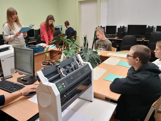 Studentes datorklasē skatās braila grāmatas.