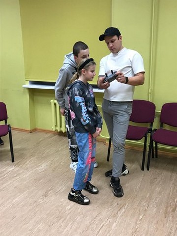 Viesis stāsa un rāda drona vadības pulti.