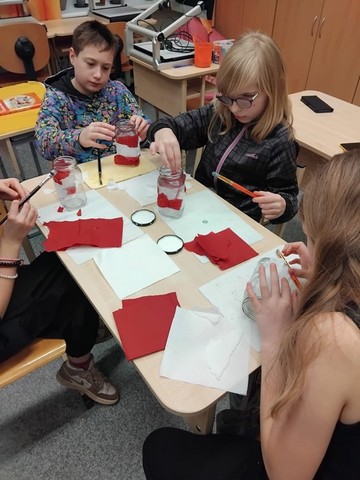 Četri skolēni pie galda zīmē ar krāsām.