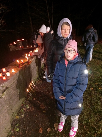 Divas meitenes pie sienas ar aizdegtām svecītēm Juglā.