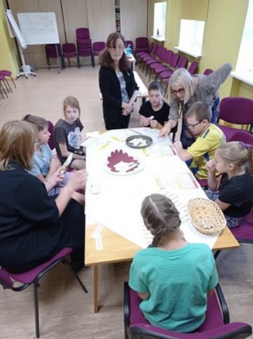 Skolēni sēž pie galda un gatavo kūkas.