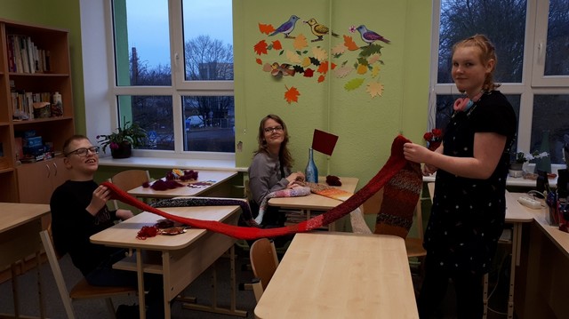 Skolēni izvērsuši garu sarkanu šalli.