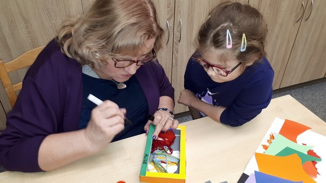 Skolotāja Dace palīdz meitenei  veidot rotājumu.