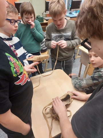 Skolēni apskata uz galda saliktās pastalas.