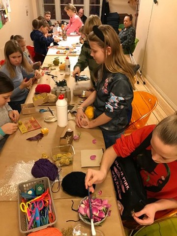 Skolēni strādā radošās darnīcās, viena meitene piecēlusies kājās.