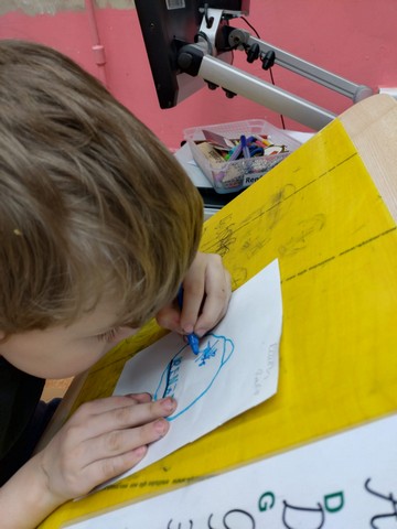 Zēns zīmē ar zilu flomasteru.