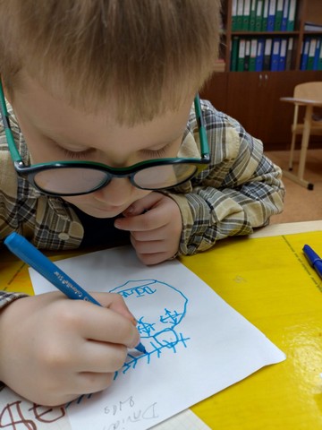 Zēns ar brillēm zīmē ar zilu flomasteru.