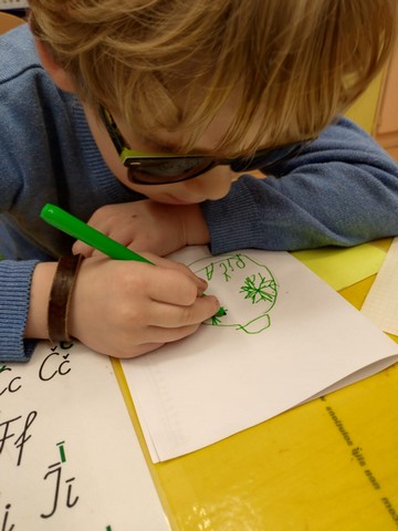 Zēns zīmē ar zaļu flomasteru.