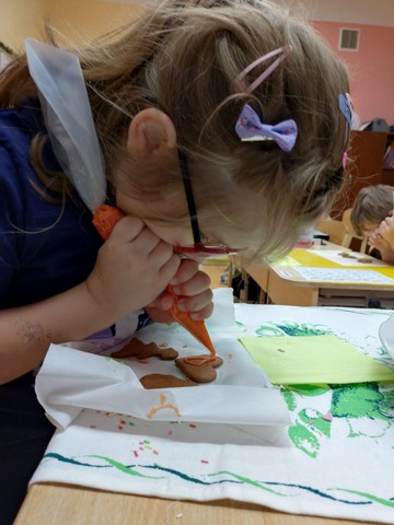 Meitene spiež no pudelītes uz piparkūkas glazūru.