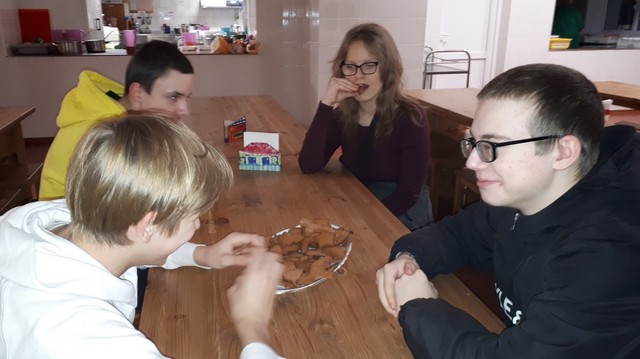 Trīs zēni un viena metene skolas ēdnīcā mielojas ar savām piparkūkām.