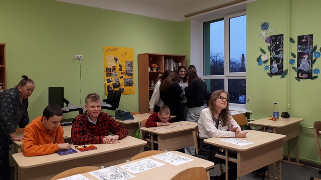 Četri skolēni sēž solos, četri - stāv un sarunājas.