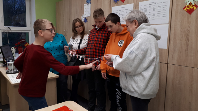 Skolēni un skolotājas Gundega un Dace izritinājuši auklu ar karodziņiem.