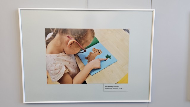 Meitene skatās grāmatu ar attēliem - krokodils un zvaigzne.