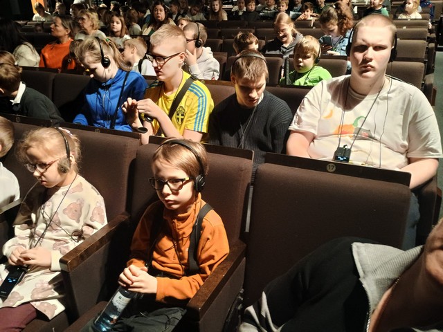 Teātra zāle pilna ar skatītājiem.