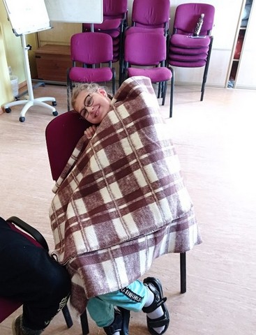 Meitene sēž krēslā ietinusies segā.