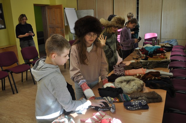 Skolēni apskata uz galda saliktos ziemas priekšmetus.