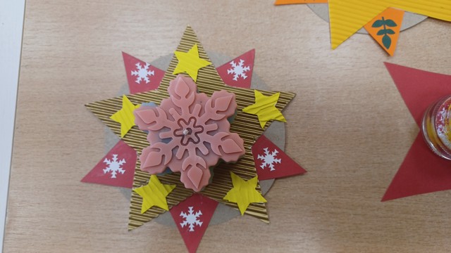 Daudzstūru zvaigzne, kurai virsū rozā svece kā sešstaru sniegpārsliņa.