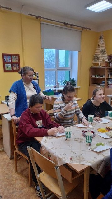 Skolēni dzer tēju un ēd gardumus.