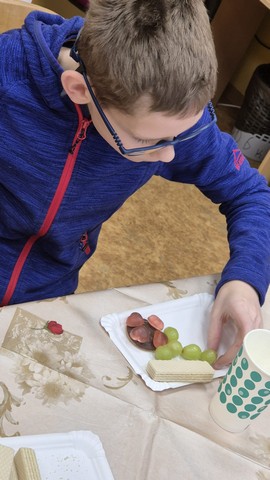 Zēns ēd no trauciņa vīnogas.