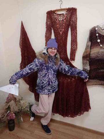 Meitene pozē pie lielas kleitas.