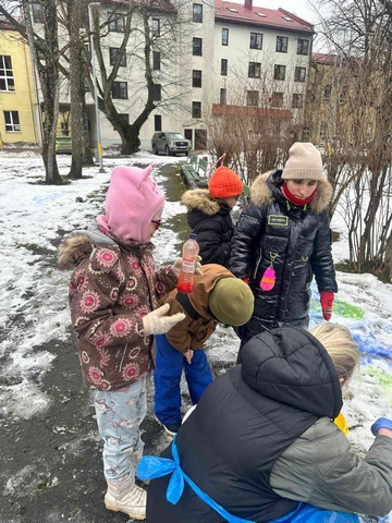Četri skolēni un viena skolotāja zīmē sniegā.